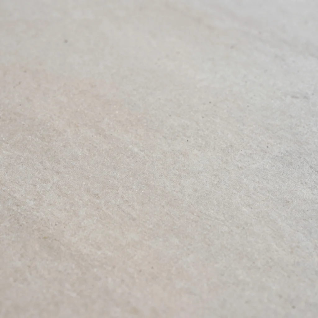 Editorial artwork photography of a quiet stone surface with fine grain, soft diffused daylight, neutral gallery tones, a